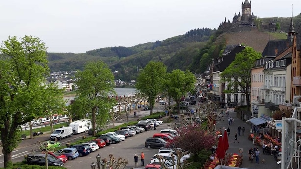 A town with a castle on a hill, parked cars, and a pedestrian street. - Hotel & Restaurant La Baia (Cochem)