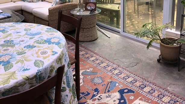 Una zona patio coperta con un angolo salotto imbottito, un tavolo rotondo e una pianta in vaso.