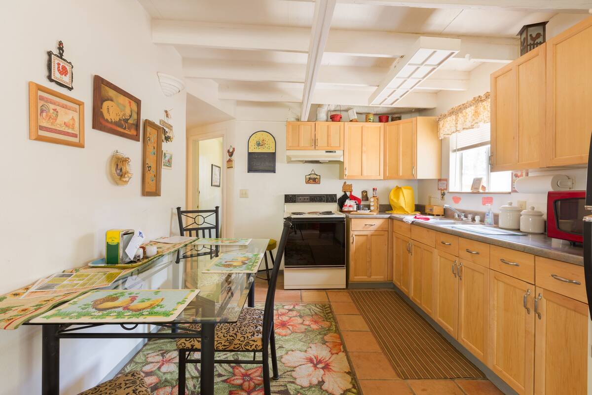 Una cocina con armarios de madera, estufa y una mesa de comedor con sillas.