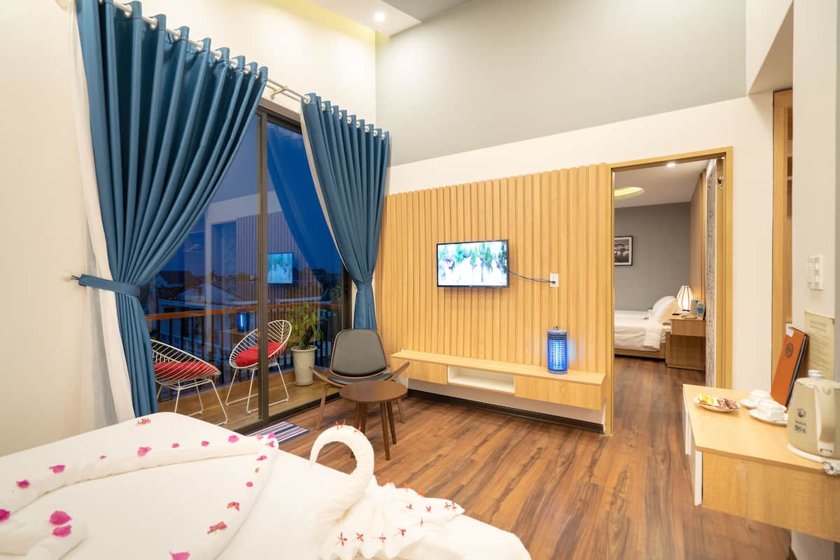 A hotel room with a bed, a TV, a desk, a chair, and a view of the outside.