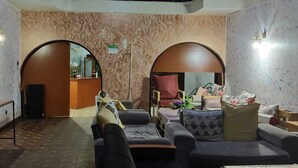 A hotel lobby with a reception desk, seating area, and decorative wall patterns. - Tisa Suites & Lounge (Kisumu)