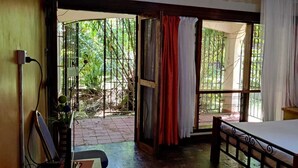 A bedroom with a bed, a window with curtains, and a view of greenery outside. - Tisa Suites & Lounge (Kisumu)