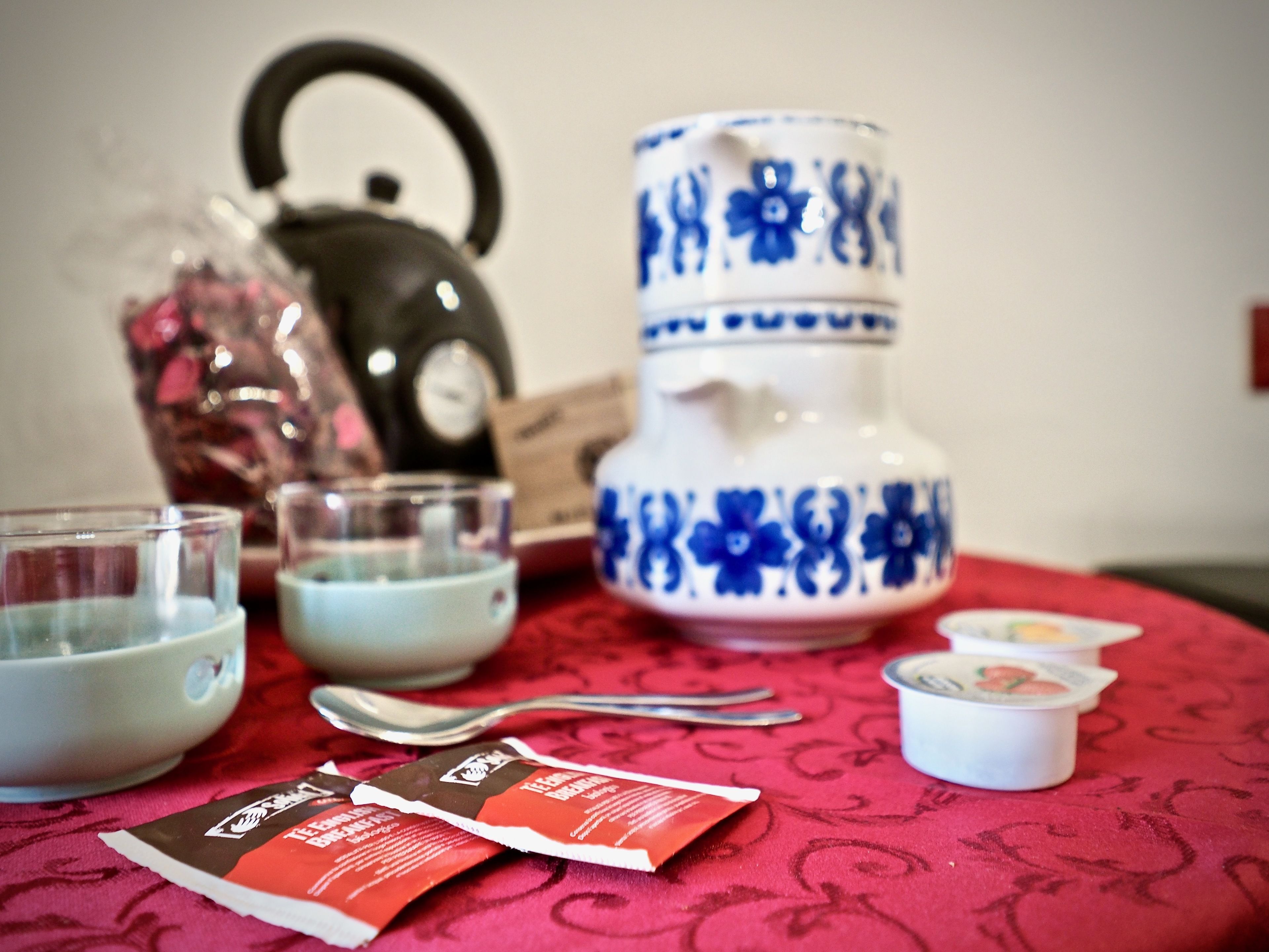Een tafel met een theepot, kopjes, een waterkoker en theezakjes.