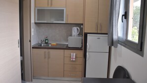 Una cocina compacta con armarios de madera, microondas, hervidor y refrigerador.