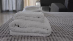 Una toalla blanca doblada con cuidado sobre una colcha con textura en una habitación de hotel.