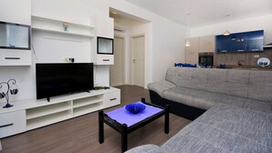 Una sala de estar moderna con un televisor de pantalla plana, un sofá gris y una pequeña mesa de centro.