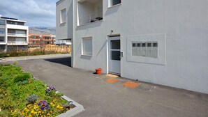 Un edificio moderno con techo plano, un balcón y una puerta con ventanal.