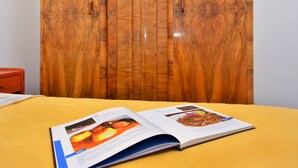 Una habitación con un armario de madera, una colcha amarilla y una revista sobre la cama.