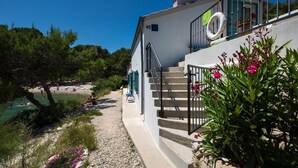 Un bâtiment situé sur la côte, doté d’un balcon, d’un escalier et offrant une vue sur la plage.