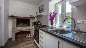 Une cuisine moderne avec une cheminée en pierre, une grande fenêtre et une vue sur la mer.