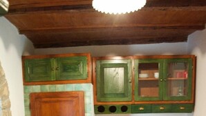 Une cuisine avec des meubles en bois, un pare-feu en carrelage et un mur en pierre.