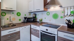 Une cuisine moderne avec des meubles blancs, un évier en acier inoxydable, une machine à café, un four à micro-ondes et une cuisinière.
