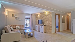 A modern living room with a sofa, coffee table, and a stone accent wall. - Antonella - Apartment Nikola (Mali Losinj)