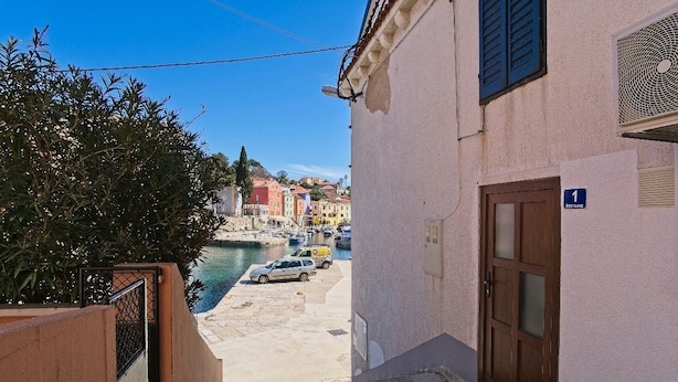 A narrow street leading to a marina with parked cars and a building with a number sign. - Antonella - Apartment Nikola (Mali Losinj)