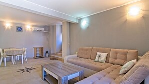 A living room with a sofa, coffee table, dining table, and chairs. There is a staircase leading to an upper level. - Antonella - Apartment Nikola (Mali Losinj)