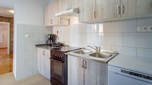 A modern kitchen with white cabinets, a built-in oven, a dishwasher, and a coffee machine. - Antonella - Apartment Antonella (Mali Losinj)