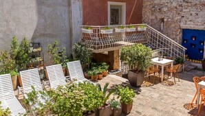 Une terrasse extérieure aménagée avec des sièges, des plantes en pot et un escalier menant à un niveau supérieur.