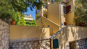 Un immeuble à plusieurs étages, avec un escalier en pierre menant à une boîte aux lettres verte.