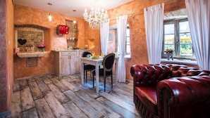 Une cuisine rustique avec une arche en pierre, un appareil électroménager rouge et une table à manger avec des chaises.
