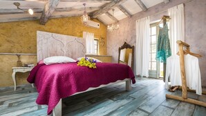 Une chambre à coucher avec un lit en bois, une table de chevet blanche, un miroir et une chaise en bois.