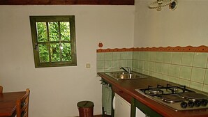 A kitchen with a window, a sink, a stove, and a dining table.