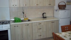 Una cocina con armarios de madera clara, una estufa a gas, un lavabo y un refrigerador.