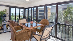 A balcony with wicker furniture, a table, and a view of the ocean. - Kings Crown 210 (Sanibel)