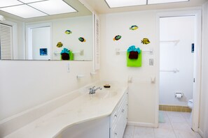 Ein Badezimmer mit einem großen Waschbecken, einem Spiegel und dekorativen Fischstickern an der Wand.