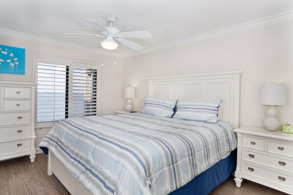 A bedroom with a bed, nightstands, a ceiling fan, and a window with blinds.
