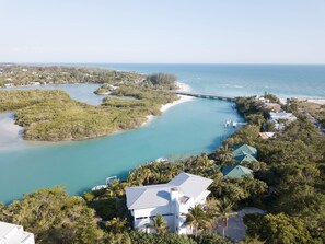 An aerial view of a coastal property with a large house, a dock, and a bridge connecting to a beach. - Sea Otter (Captiva)