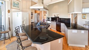A modern kitchen with a central island, bar stools, and stainless steel appliances. - Sea Otter (Captiva)