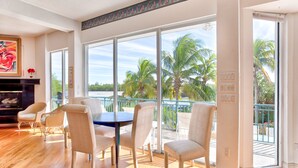 A spacious room with a large balcony, a dining area with chairs, and a fireplace. - Sea Otter (Captiva)