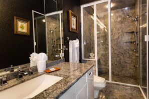 A modern bathroom with a large sink, two mirrors, a shower enclosure, and marble walls. - Sea Otter (Captiva)