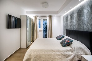 A modern bedroom with a large bed, a flat-screen TV, a wardrobe, and a view of the outdoors. - Dubrovnik Spectrum Rooms (Dubrovnik)