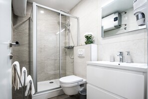 A modern bathroom with a glass-enclosed shower, a toilet, and a sink with a mirror above. - Dubrovnik Spectrum Rooms (Dubrovnik)