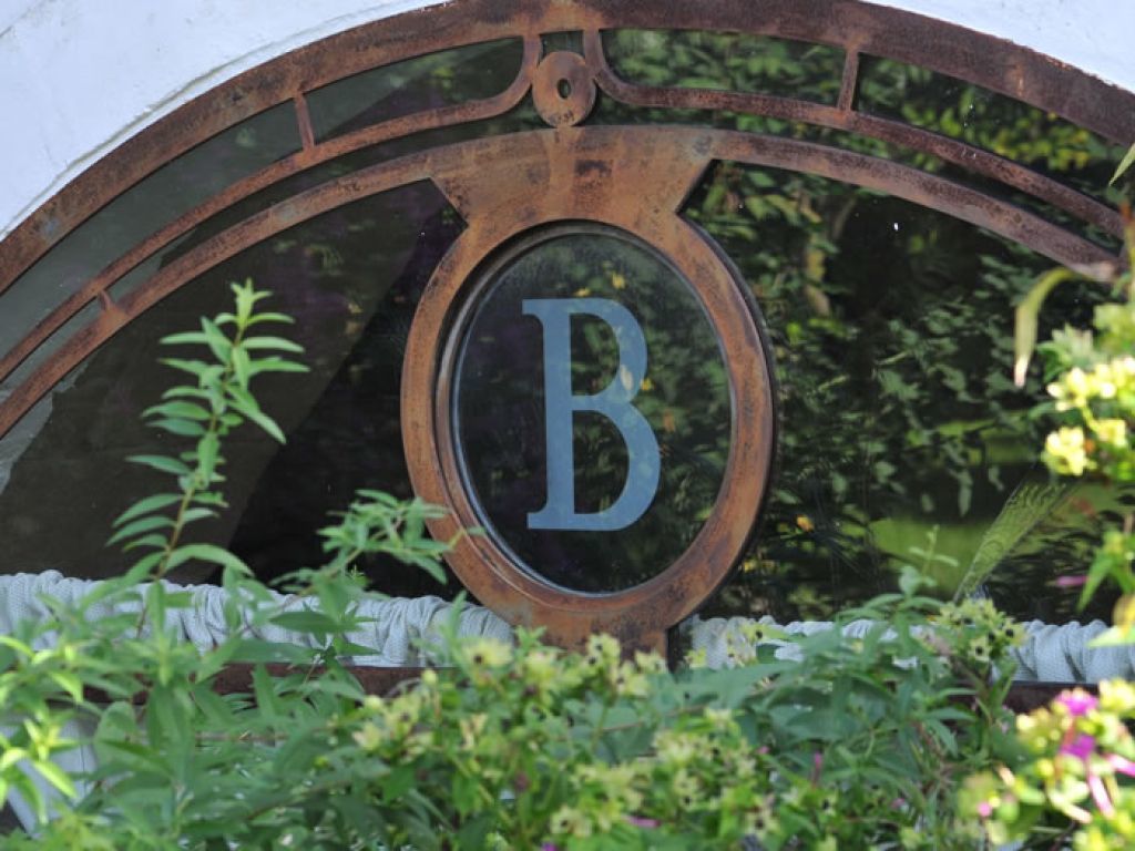 A circular window with a letter 'B' in the center, surrounded by greenery.