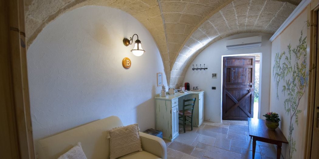 Un intérieur chaleureux avec un plafond incurvé, un coin repas avec une table et des chaises en bois, et un espace cuisine doté d’un comptoir et de placards.