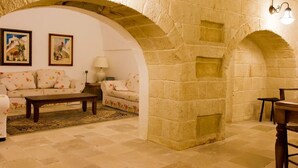 A cozy living room with a stone wall, a sofa set, a coffee table, and a lamp. - Masseria La Brunetta (Massafra)