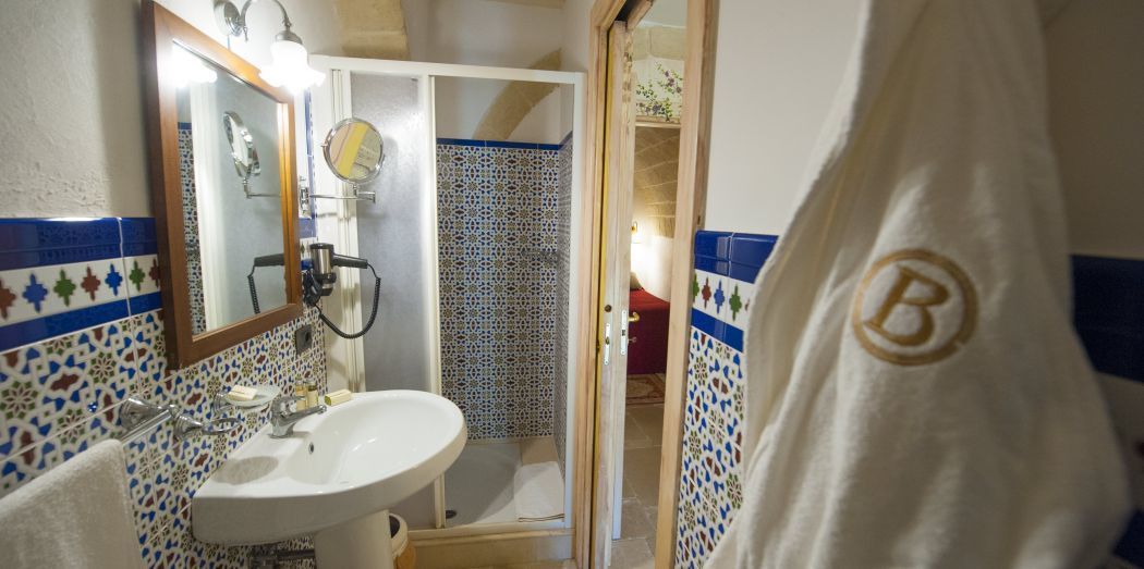 Ett badrum med ett vitt handfat, en spegel och en duschhörna.