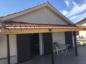 A covered outdoor area with a tiled roof, a wooden pergola, and a table with chairs. - Rose place (Spata-Artemida)