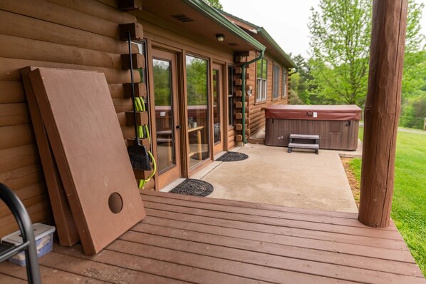 Una baita di legno con veranda, porte scorrevoli in vetro e vasca idromassaggio.