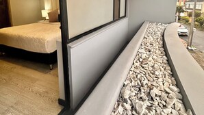 Une chambre d’hôtel moderne avec un lit, une grande fenêtre et un chemin bordé de pierres.
