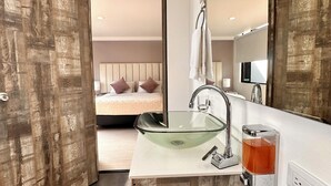 Une salle de bain moderne avec un lavabo en verre, un miroir et un distributeur de savon.