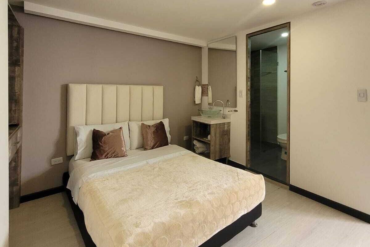 Ein modernes Schlafzimmer mit einem großen Bett, einem Nachttisch, einem Spiegel und einem durchgegangenes Badezimmer.
