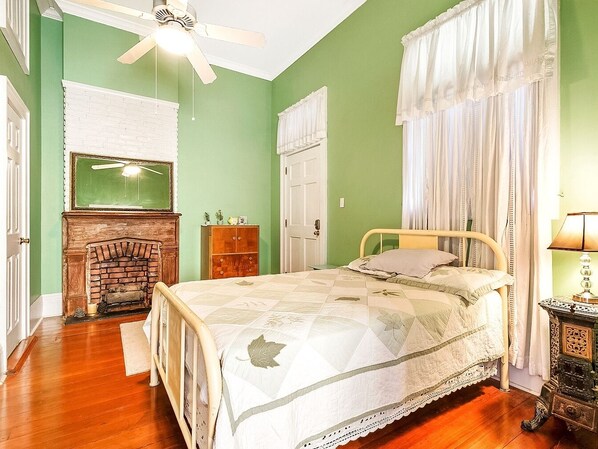 A bedroom with a bed, a fireplace, a ceiling fan, and a nightstand.