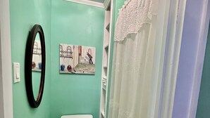 Ein kleines Badezimmer mit Toilette, Spiegel und Duschvorhang.