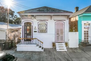 A white house with a number 704, a front porch with steps, and a small garden area. - Great location in the historic Marigny area (New Orleans)