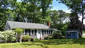 A single-story house with a front porch, a small shed, and a well-maintained lawn. - Lovely three bedroom home with access to Swan Pond (Dennis Port)