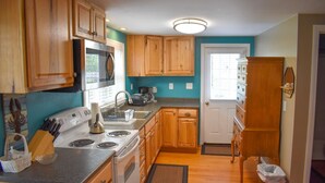 A kitchen with wooden cabinets, a white stove, and a microwave. - Lovely three bedroom home with access to Swan Pond (Dennis Port)
