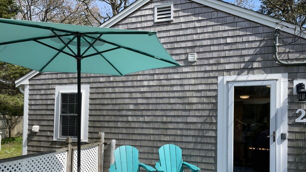 A house with a porch, a table, two chairs, and an umbrella. - Lovely three bedroom home with access to Swan Pond (Dennis Port)